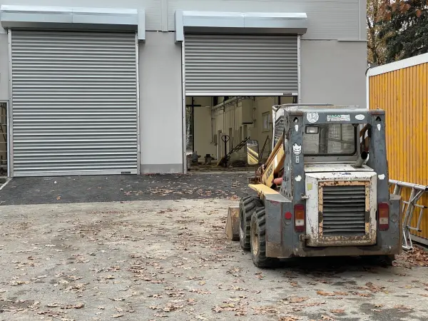 Rolovací průmyslová vrata Hörmann Decotherm DD s opláštěním nábalu a pohonu, montáž na fasádu.