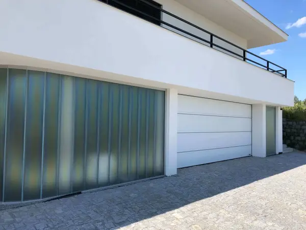 Sekční bílá garážová vrata Hörmann LPU, drážka "T" s ozdobným vodorovným nerezovým pruhem, hladký povrch SilkGrain na moderní vile. Jednoduché a elegantní řešení vrat do garáže.